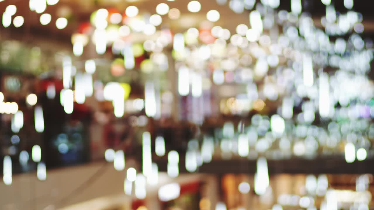 Christmas lights bokeh background adorn the floor of a large modern shopping center. Blurred bright Christmas lighting in the mall