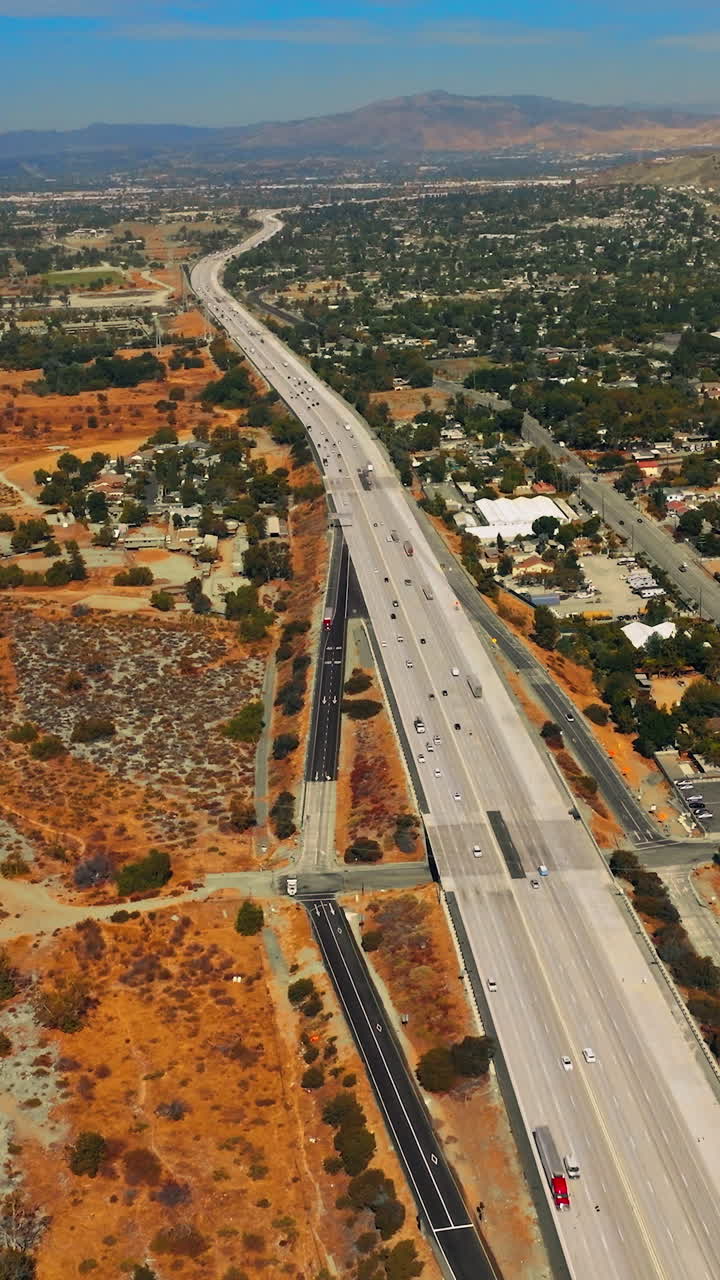 Dry landscape of Los Angeles outskirts on hot sunny daytime. Roads going through sandy lands. Mountain at backdrop. Vertical video