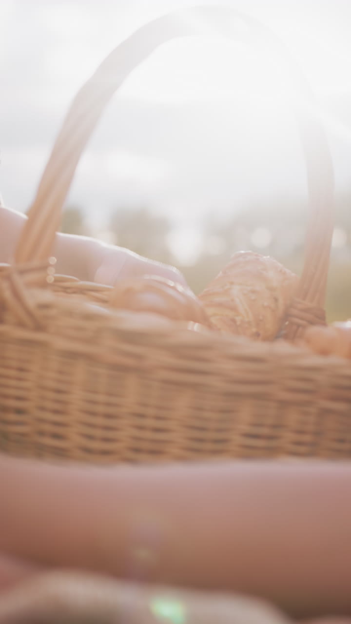 피크닉을 위해 야외에 앉아있는 어머니와 아이들의 클로즈업, 인 손을 가진 여자가 누군가가 지나갈 때 바구니에서 간식을 얻습니다.