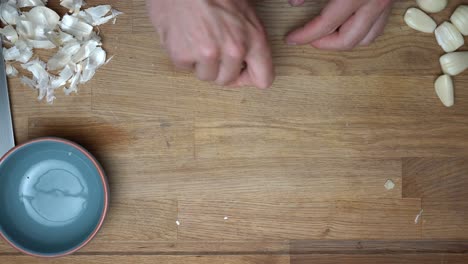 top-down-of-hands-peeling-several-cloves-of-garlic