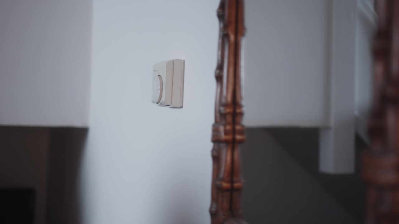 mujer ajustando el termostato para ahorrar dinero en facturas de energía durante la crisis del costo de la vida de cerca