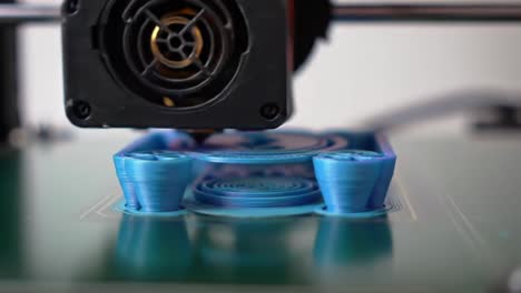 a close-up view of a blue object being printed by a 3d printer in a contemporary workspace. the machine operates smoothly, demonstrating advanced technology in action.