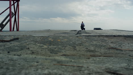 fisherman fishing river pier using rod on grey weather. people catching fish.