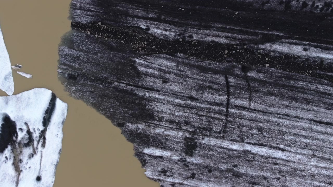 Drone close-up of dark volcanic ash bands streaking across Hoffellsjokull Glacier ice, aerial top down backdrop texture, nobody
