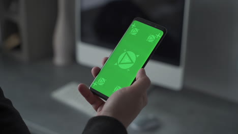 Smartphone with vertical green screen chroma. Mockup. Telecommuting, having a videocall sending and receiving messages. Close-up.