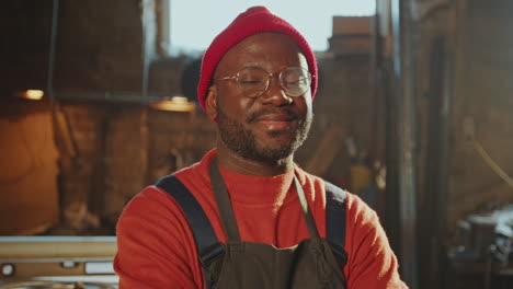 portrait of cheerful african american blacksmith at workplace