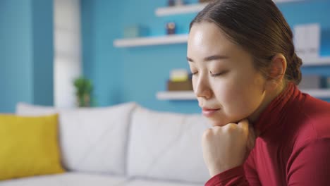 거실에 앉아 있는 사려 깊고 불행한 아시아 여성.