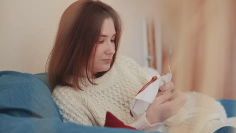 a red haired young female cross stitching