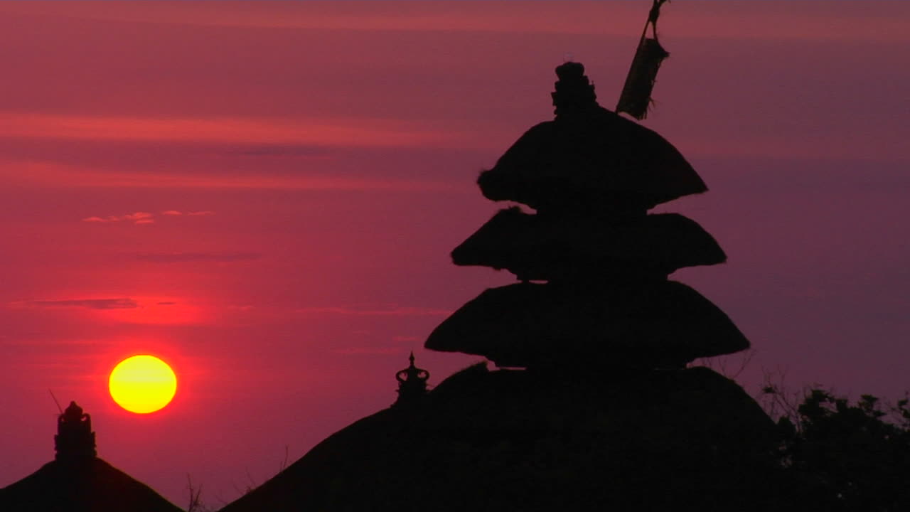 Il Tempio Pura Tanah Lot si staglia in silhouette contro un cielo luminoso