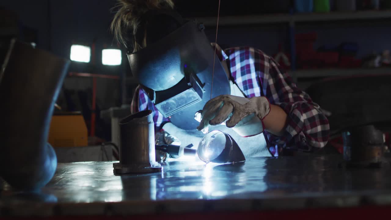자동차 서비스 스테이션에 앉아있는 동안 용접 헬 ⁇ 을 착용 한 여성 메카닉 용접