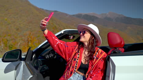 woman taking a selfie in a convertible car