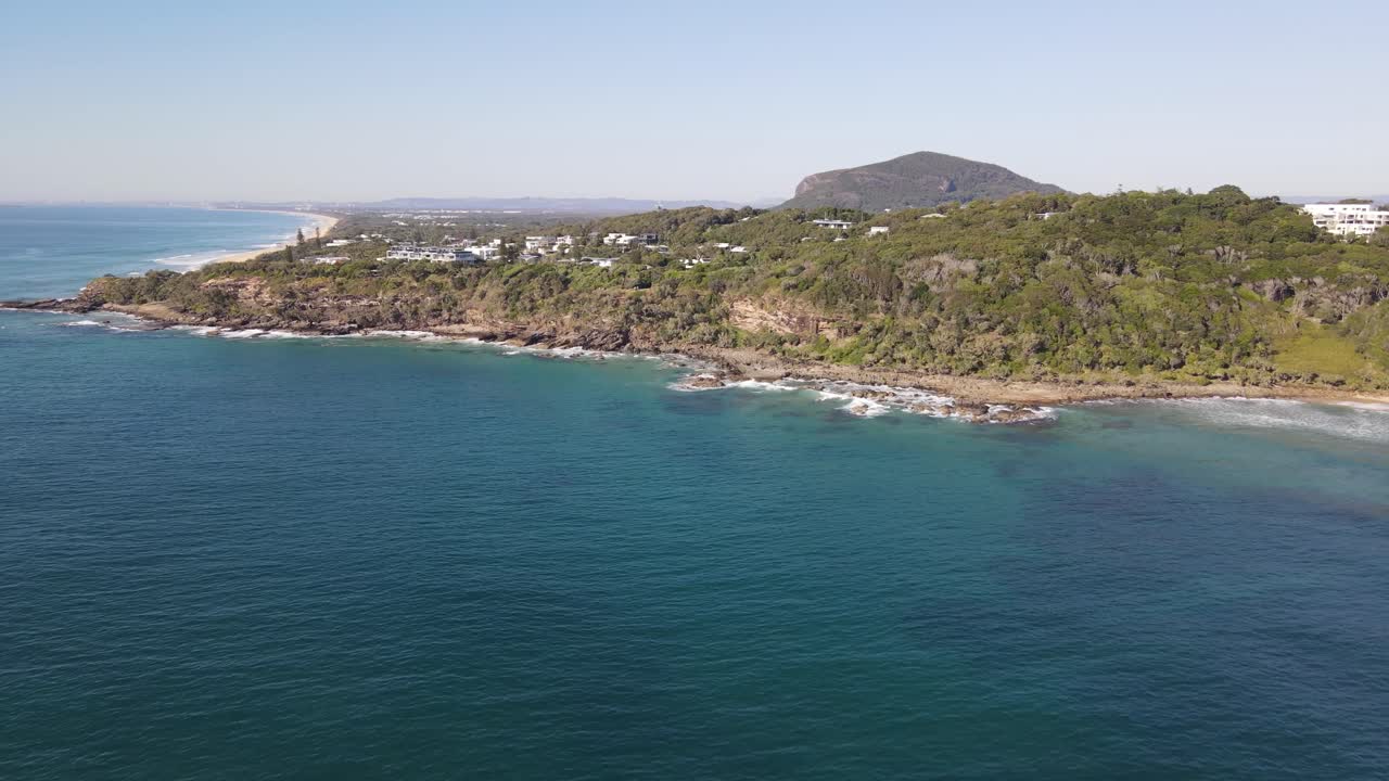 Drone aerial moving forward towards a coastal area in coolum beach on a sunny day
