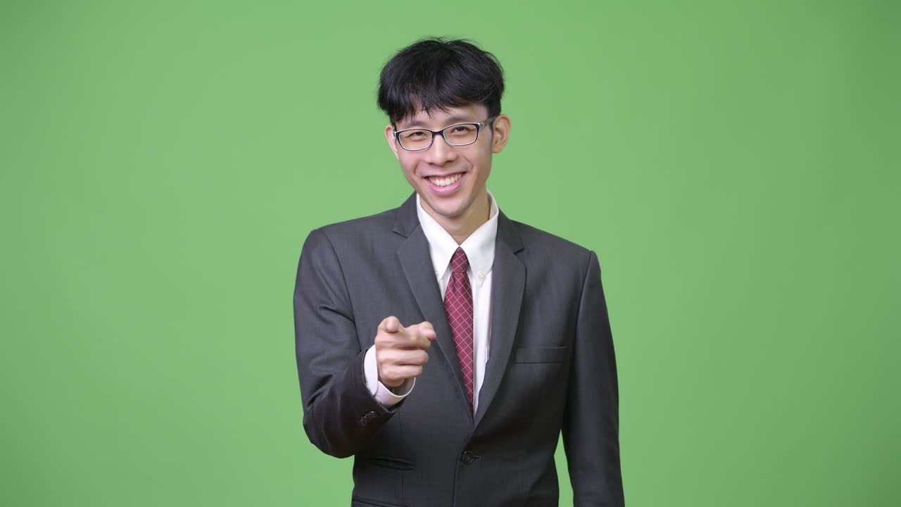 젊은 행복한 아시아 사업가 가 카메라 를 가리키면서 미소 짓고 있다