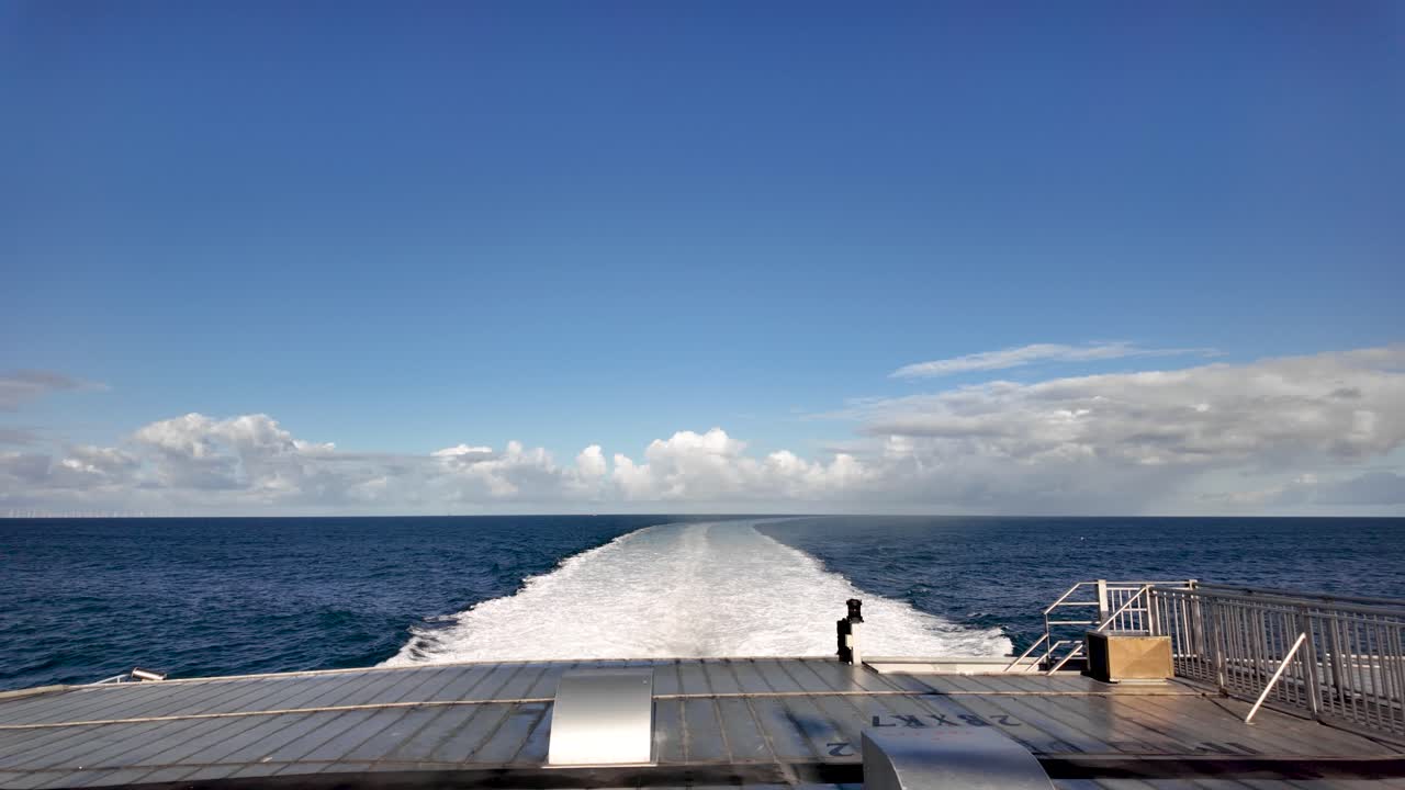 Ship sailing across the Irish Sea, leaving a white wake under a blue sky. slow motion