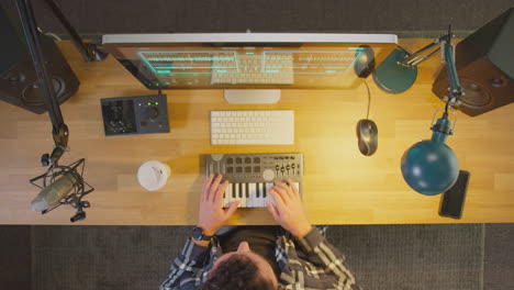 overhead view of male musician at workstation with keyboard and microphone in studio