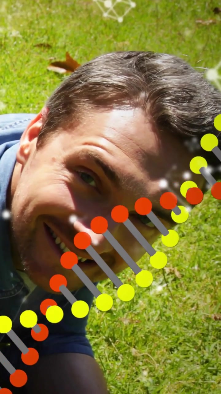 Video verticale: Uomo sdraiato sull'erba che inclina la testa, con sovrapposizione di DNA in movimento e scintille per mostrare la salute
