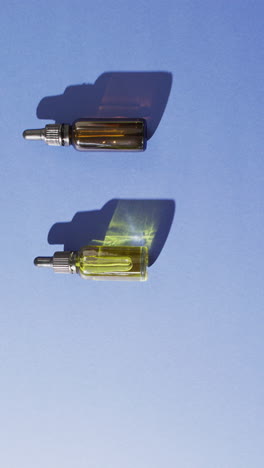 vertical video of dropper serum bottles on blue background with copy space