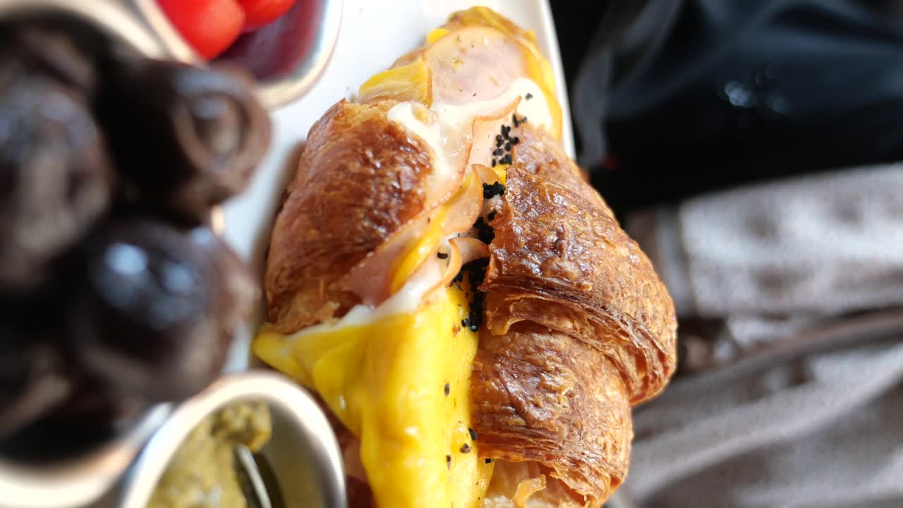 Primo piano di un gustoso croissant farcito con prosciutto e formaggio fuso