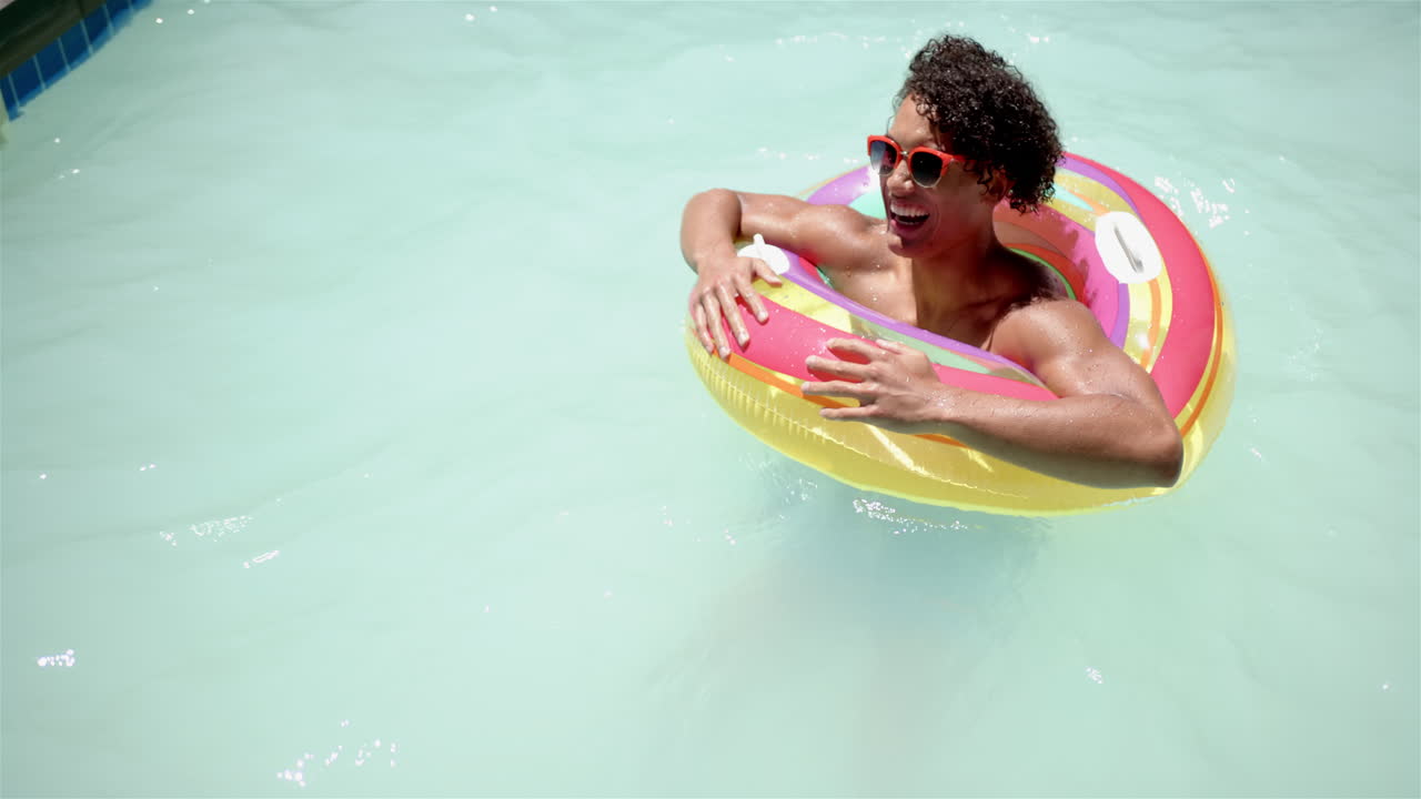 Enjoying summer, man relaxing in pool with colorful inflatable ring, copy space