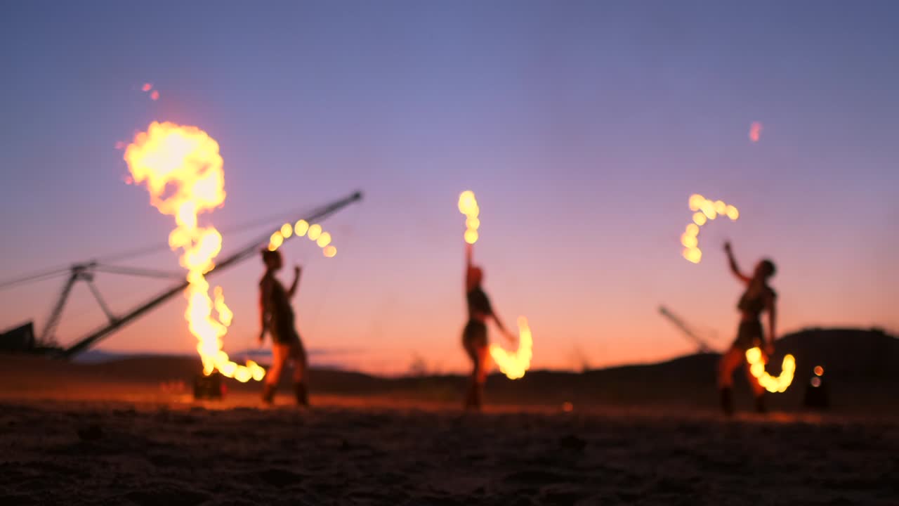 artistas profesionales muestran un espectáculo de fuego en un festival de verano en la arena en cámara lenta. acróbatas de cuarta persona de circo trabajan con fuego por la noche en la playa.