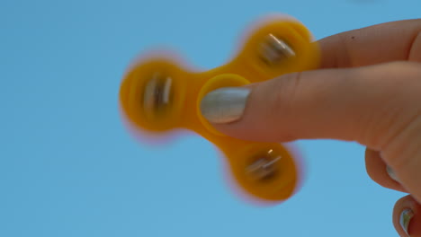 playing with yellow fidget spinner on sky background