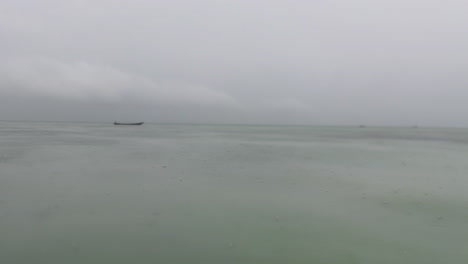a boat in the distance on a cloudy, rainy day