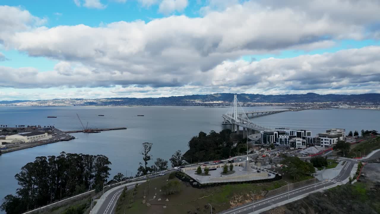 A smooth drone push-in reveal shot of The Bay Bridge from Yerba Buena Island, CA, showcasing the bridge and scenic bay. Ideal for urban, transportation, and travel footage.