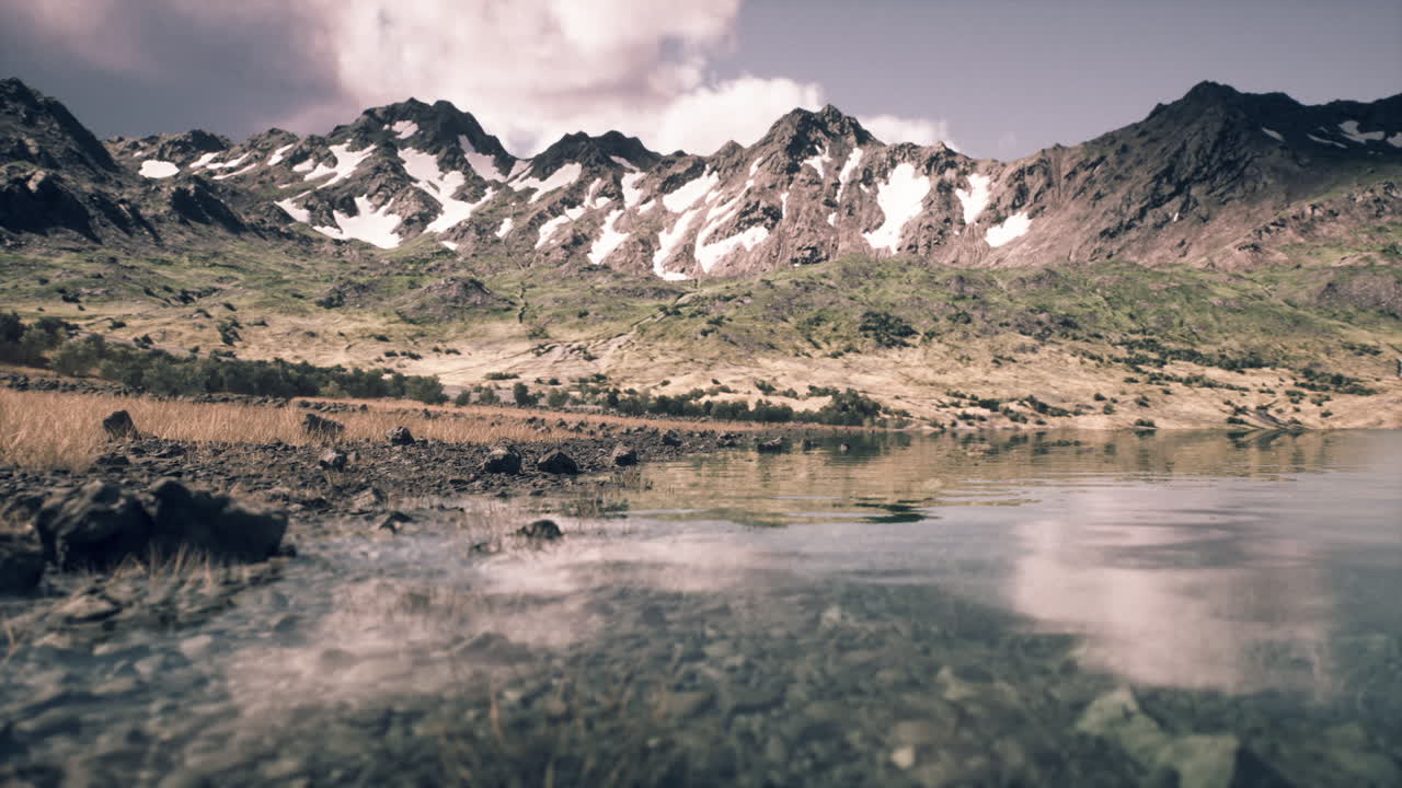 Calm lake reflects snow capped mountains under a bright sky in serene landscape