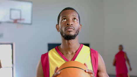 african american man holds a basketball in a gym