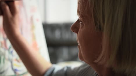 Close-up-video-of-senior-woman-painting-while-sitting-at-home.