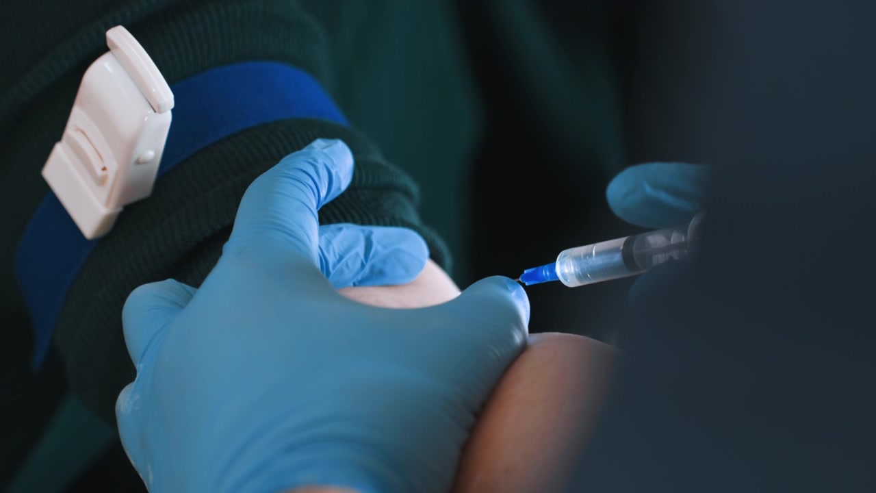 Closeup tourniquet tightened on arm before draw, gloved hands prepare syringe and vial, steady pressure on vein, clinical precision in residence, sample collection for lab, focused emergency care