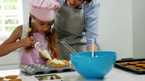 Mutter-Hilft-Mädchen,-Cupcake-Mit-Sahne-Zu-Dekorieren