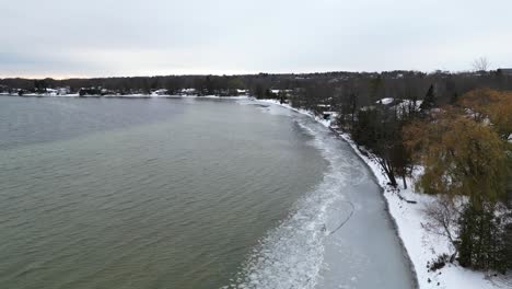 Flying-over-ice-build-up-on-the-coastline-of-lakeshore-houses