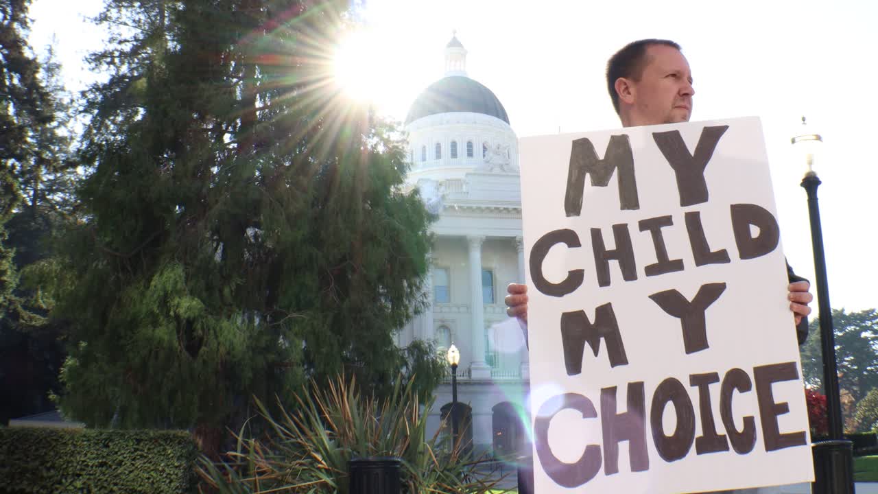 Protestor holding a sign that says 'My Child My Choice' outside the California State Capitol