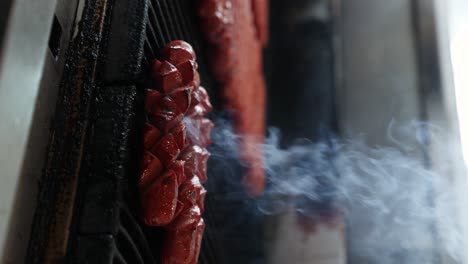 persona utiliza pinzas de metal para mover salchichas de perritos calientes en la parrilla, video vertical