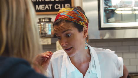 Young-woman-advising-a-customer-at-a-butcher's-shop