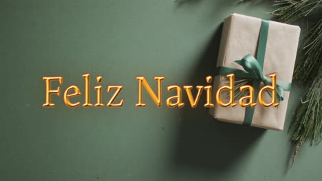 feliz navidad texto en naranja sobre regalo de navidad en fondo verde