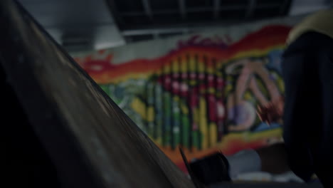 Active-man-practicing-skateboard-at-skate-park-with-graffiti-on-wall.