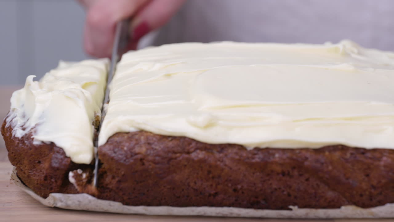 Mulher fatiando seu bolo de cenoura assado com morangos frescos em uma tábua de corte de madeira - slider para a direita, close-up.