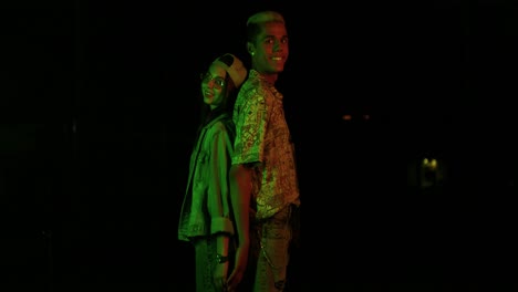 teenager african american boy and caucasian girl with glasses and cap touching their backs and looking at camera