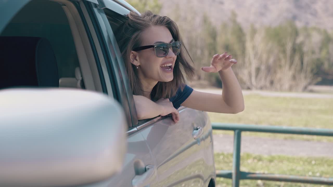 una mujer de cabello corto agita la mano inclinándose hacia fuera del primer plano automático