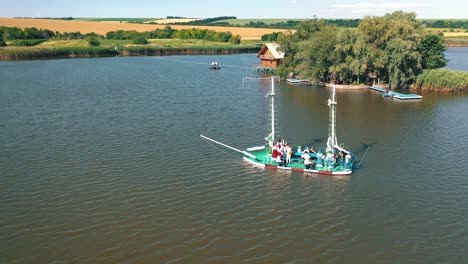 old boat floating near the island with house in the river. island with green trees surrounded by water on the natural background in summer. aerial view.