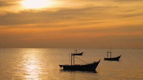 los barcos flotan pacíficamente en un mar dorado al atardecer.