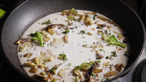 fresh milk poured into vegetables cooking in a pan
