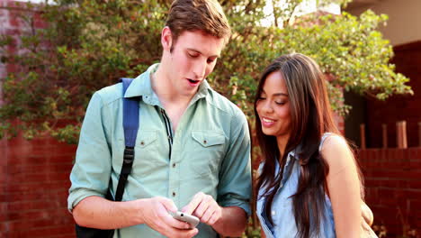 two students standing and looking at smartphone