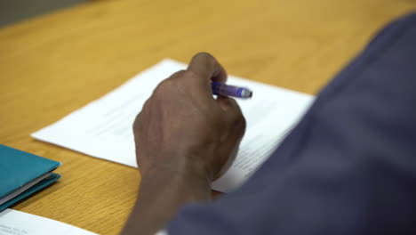 Inmate-writing-homework-in-school-while-in-prison-jail-incarcerated-behind-bars-black-african-american