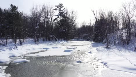 stream running through forest covered in snow low flight beauty