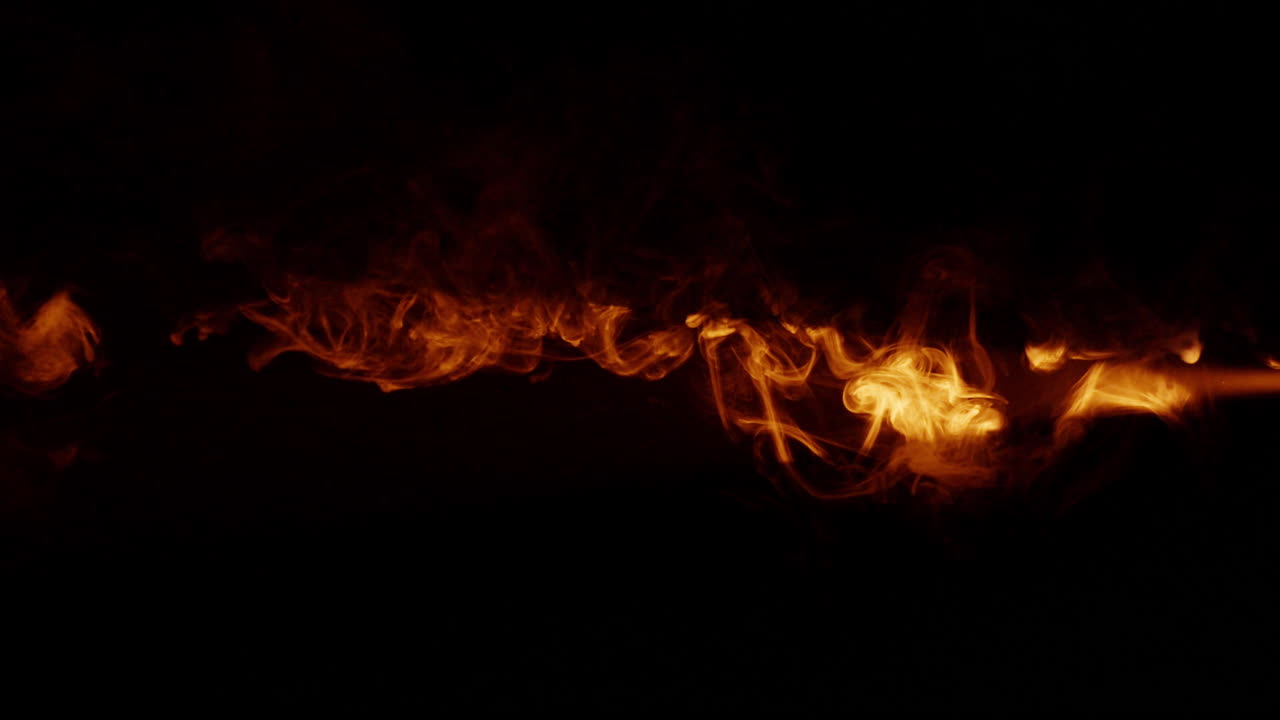 Fiery orange smoke on dark background flowing slowly ethereal fog