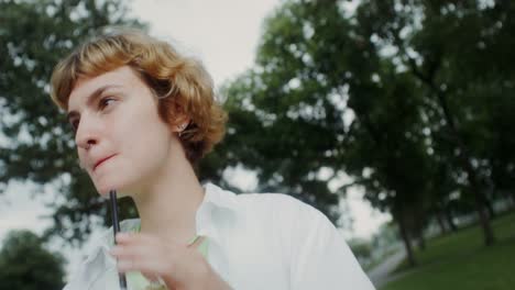 young woman enjoying a smoothie in the park