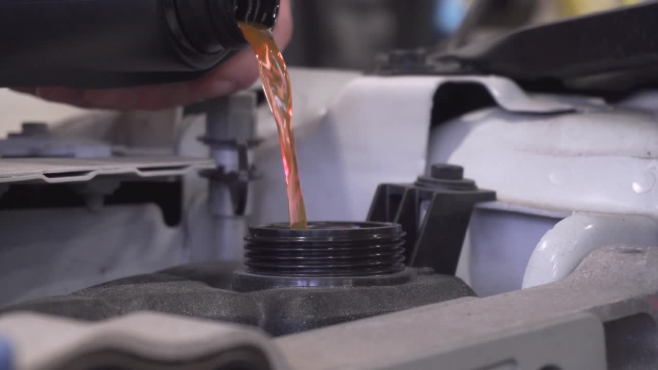 자동차 정비사가 빨간색 냉각수를 차 안의 탱크에 채우는 정적 샷